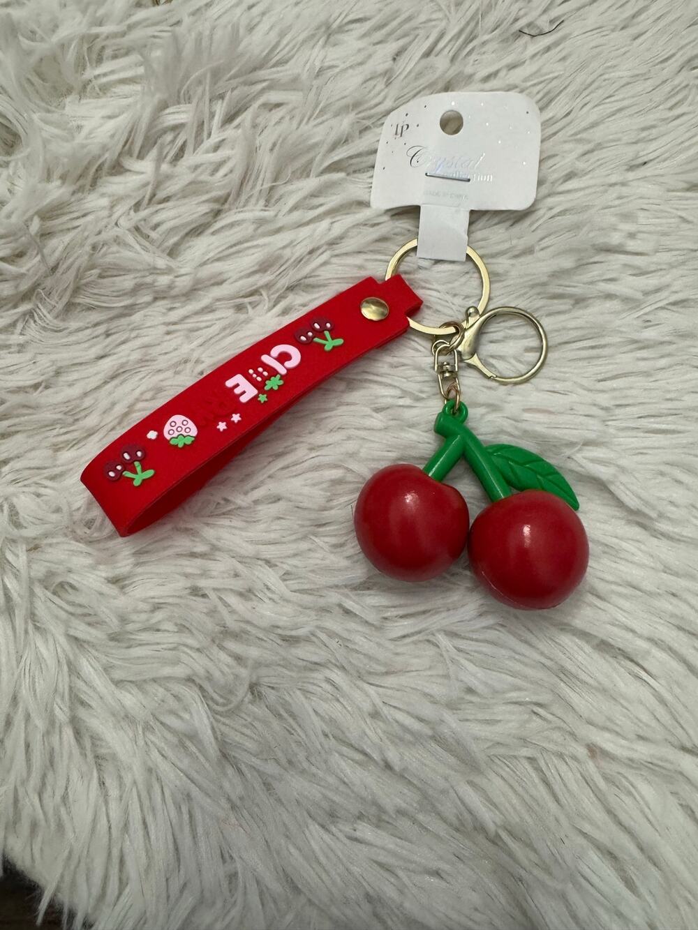 Red rubber cherry keychain bag charm with green stems and leaves